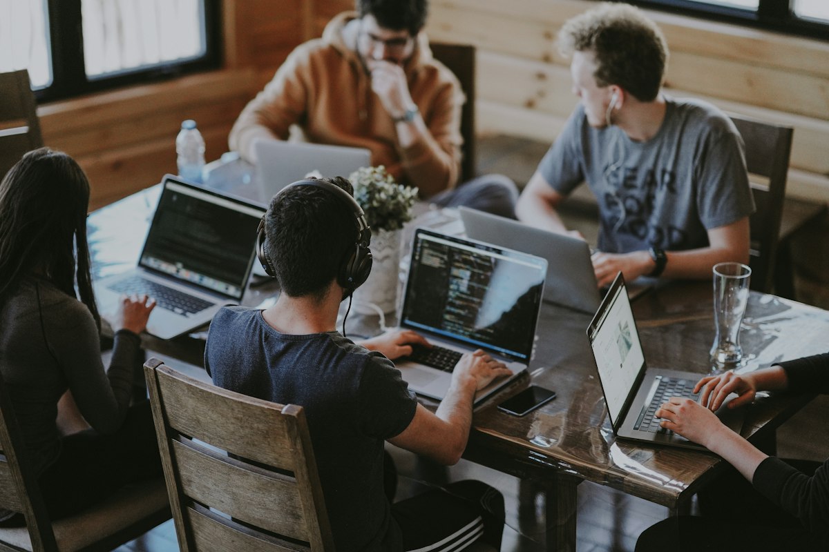 Engineering and product leads collaborating around laptops in a timber studio